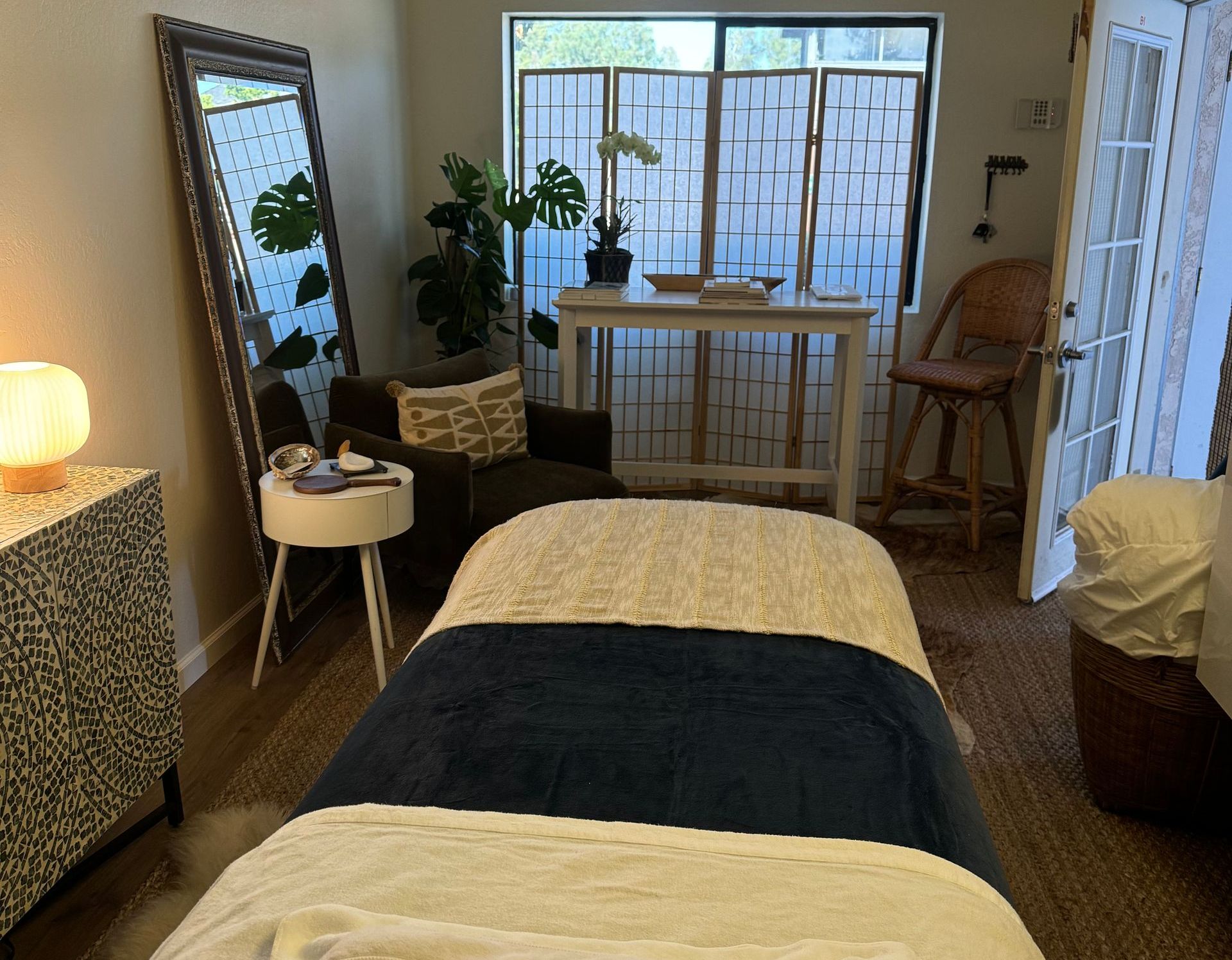 A massage table in a room with a mirror and chairs