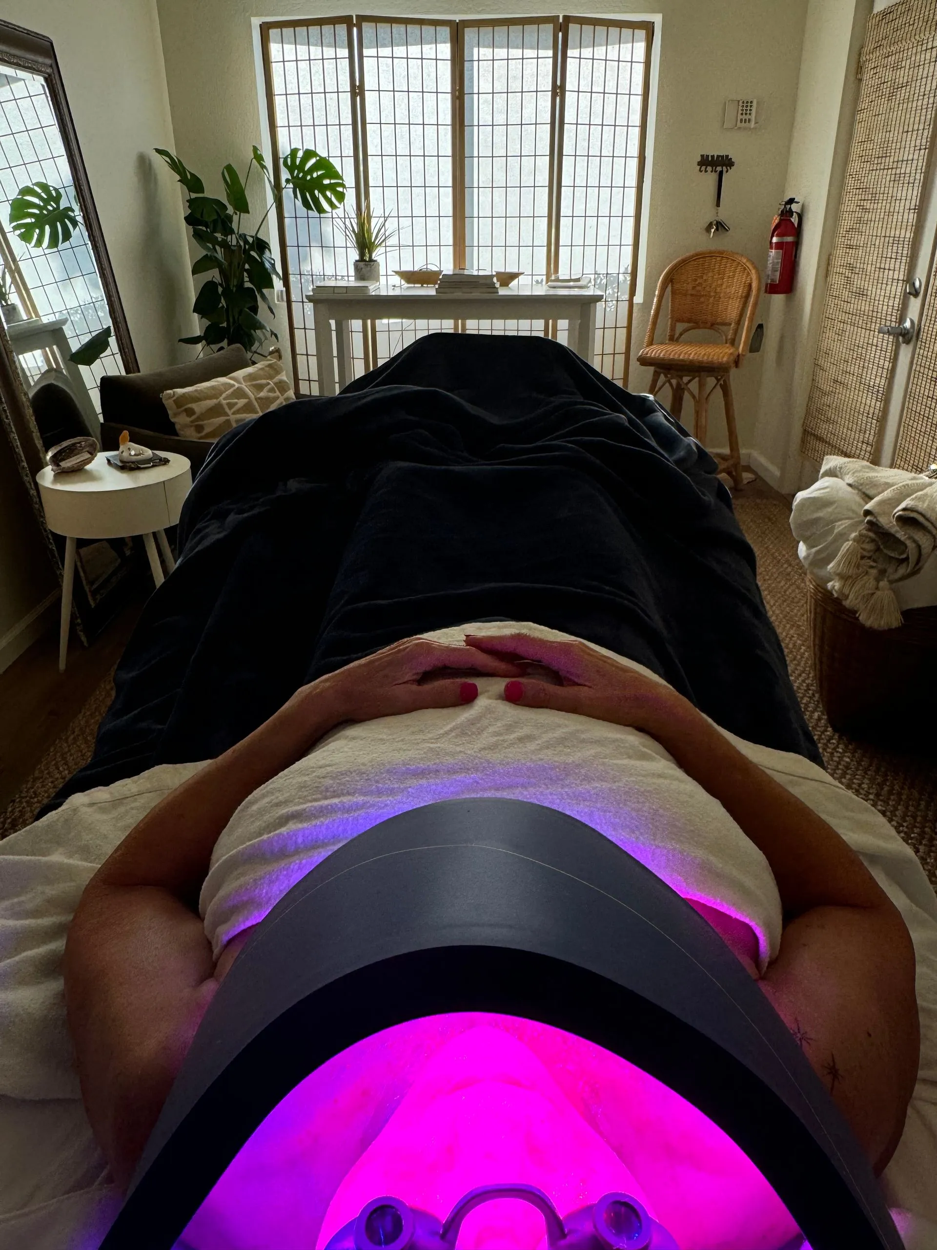 A woman is laying on a bed with a purple light on her face.