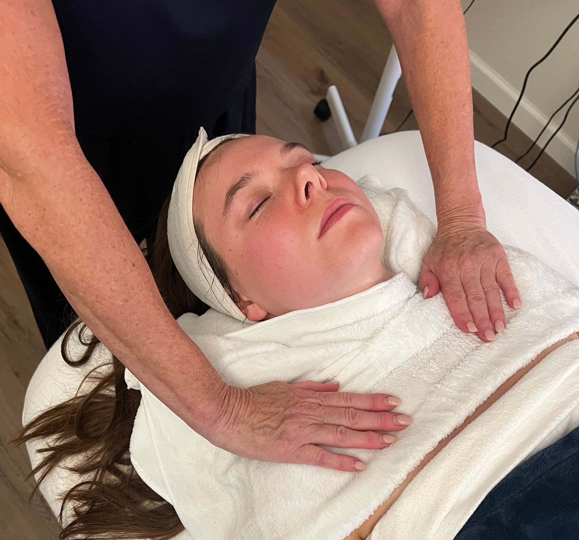 A woman is laying on a table with her eyes closed getting a massage.