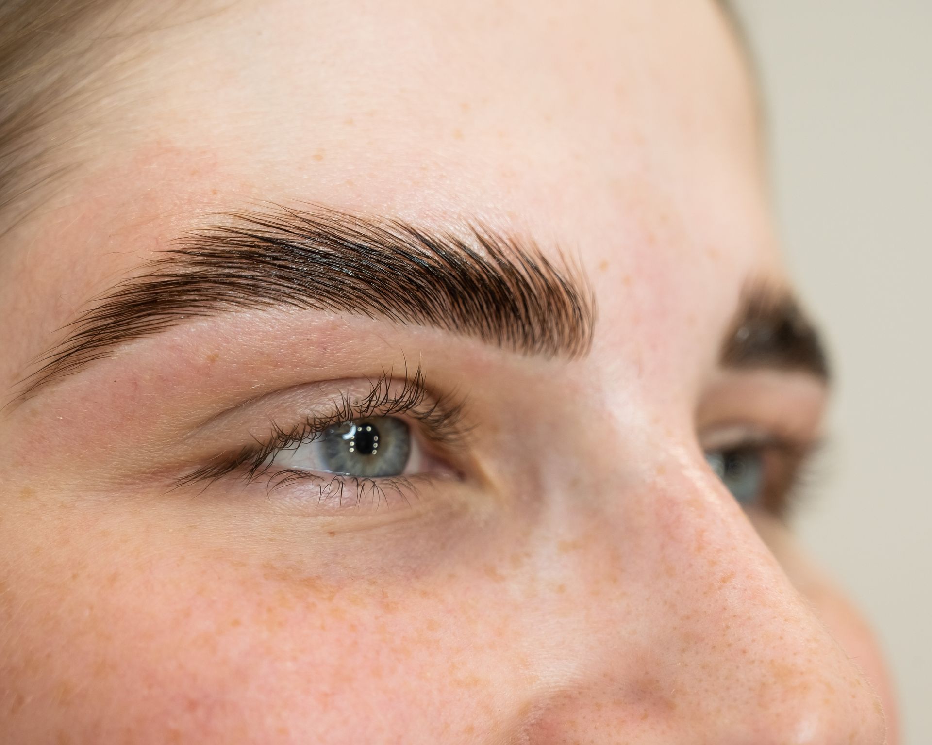 A woman is getting her eyebrows painted with a brush.